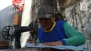 Sutayono menyelesaikan jahitan pelanggan di kawasan Matraman, Jakarta, Jumat (24/7/2020). Pria 74 tahun itu rencananya berangkat haji pada 2022 mendatang usai melunasi administrasi sejak 2016 silam dari hasil menjahit, namun keberangkatannya harus diundur akibat Covid-19. (merdeka.com Imam Buhori)