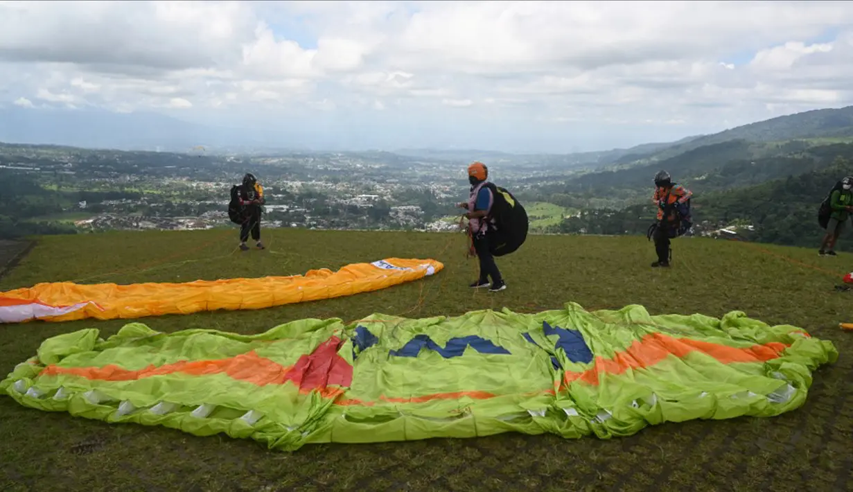 Paraglider bersiap untuk lepas landas dari lereng bukit di Puncak, Bogor, Jawa Barat, Kamis (2/12/2021). Destinasi wisata alam Bukit Paralayang Puncak Bogor sangat cocok untuk dikunjungi pada liburan akhir pekan bersama keluarga, sahabat maupun pasangan tercinta. (Goh Chai Hin/AFP)