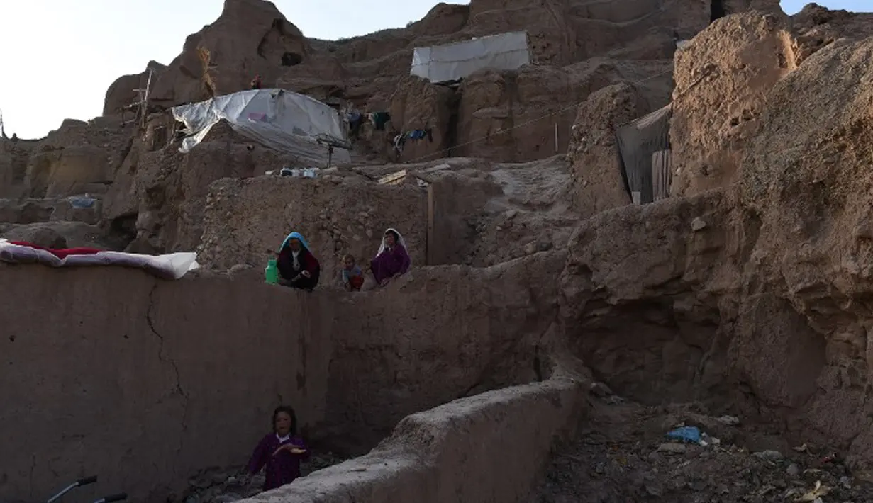 Seorang wanita mencuci piring di depan gua di kota Bamiyan, Kabul. Foto diambil 19 Juni 2015. Ratusan warga miskin Afghanistan terpaksa menghuni gua-gua tersebut untuk dijadikan rumah karena tak memiliki tempat tinggal. (AFP PHOTO / SHAH Marai)