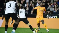 Pemain depan Real Madrid asal Brasil #7, Vinicius Junior ​​(kanan), mencoba menggiring bola melewati gelandang Valencia asal Argentina #05, Enzo Barrenechea (tengah), selama pertandingan Liga Spanyol antara Valencia CF dan Real Madrid CF di stadion Mestalla di Valencia, Sabtu dini hari (4-1-2025). (JOSE JORDAN/AFP)
