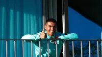 Cristiano Ronaldo yang terjangkit COVID-19 tampak semringah menyaksikan rekan-rekannya di timnas Portugal berlatih dari balkon kamar hotelnya, Selasa (13/10/2020) (AFP/Diogo Pinto)