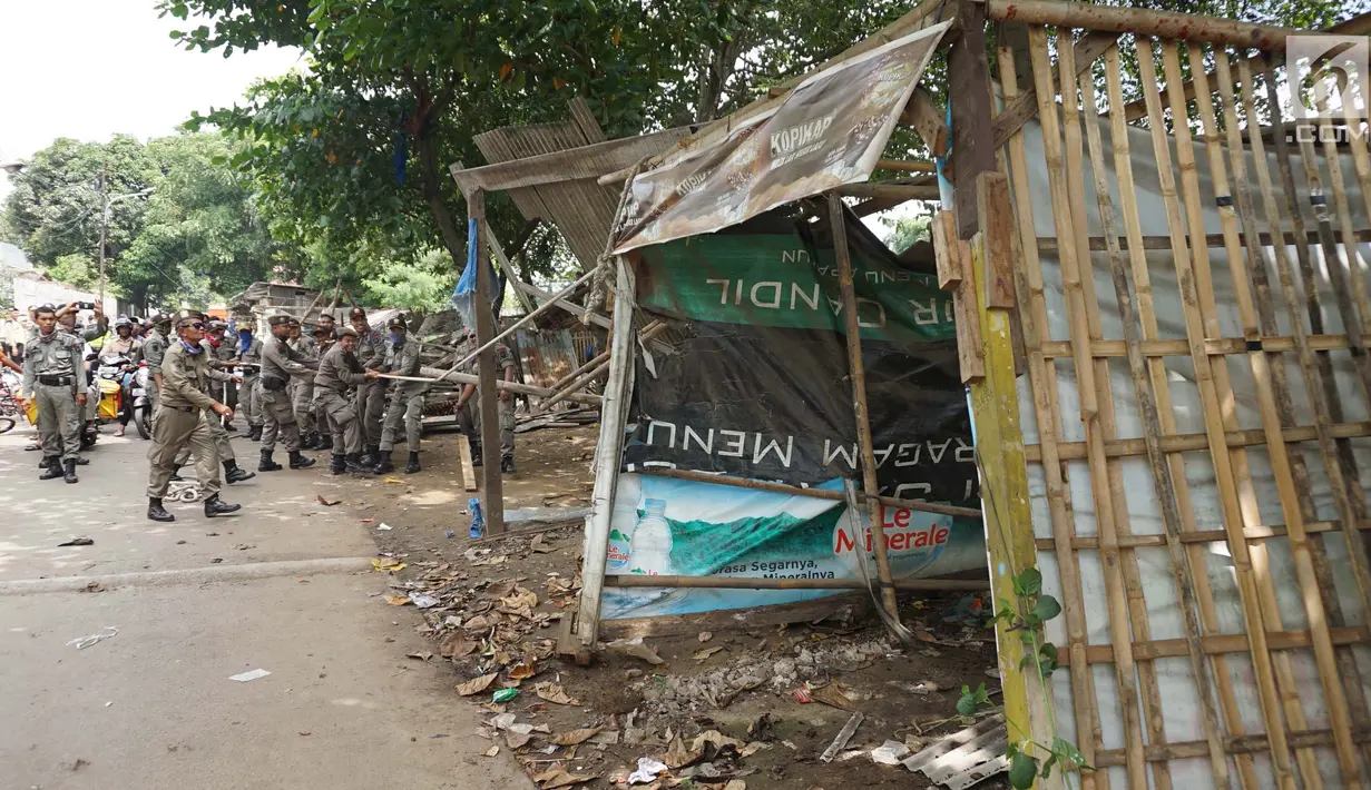 Petugas Satpol PP menarik tali untuk merobohkan bangunan liar di Jalan Desa Semanan, Kalideres, Jakarta Barat, Senin (9/4). Nantinya kawasan tersebut akan digunakan untuk pembangunan taman. (Liputan6.com/Arya Manggala)