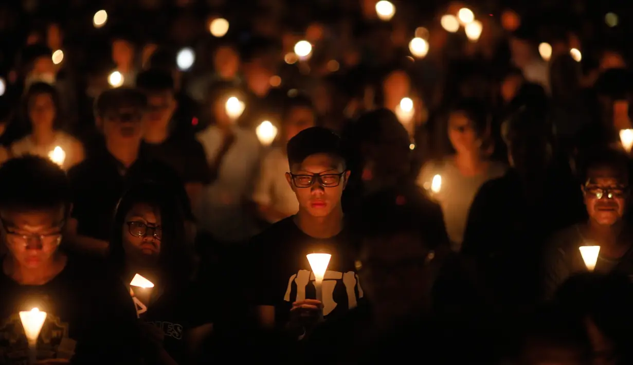 Sejumlah orang memegang lilin sambil berdoa untuk memperingati Insiden Tiananmen di Taman Victoria Hong Kong (4/6). Aksi protes bersejarah itu memakan korban lebih dari 3.000 orang meninggal akibat tindakan dari pasukan bersenjata. (AP/Vincent Yu)