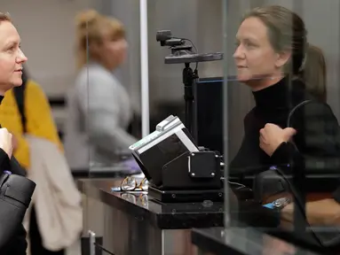 Penumpang dari Denmark, Katrina Poulsen berdiri di depan kamera pemindaian wajah setibanya di bea cukai Bandara Internasional Orlando, Florida, Kamis (21/6). Bandara ini menjadi yang pertama di AS yang menerapkan sistem pemindaian wajah. (AP/John Raoux)