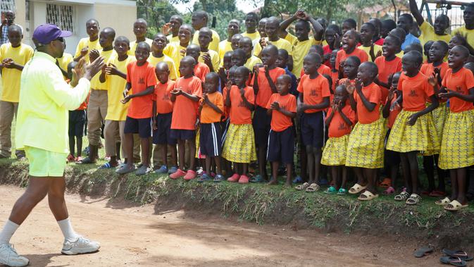 Rapper AS, Kanye West bertepuk tangan sambil bernyanyi bersama anak-anak dalam kunjungannya ke Kampung Anak UWESCO di Masulita, Uganda, Selasa (16/10). Ditemani Kim Kardashian, Kanye West berada di Uganda untuk misi kemanusiaan. (AP/Stephen Wandera)
