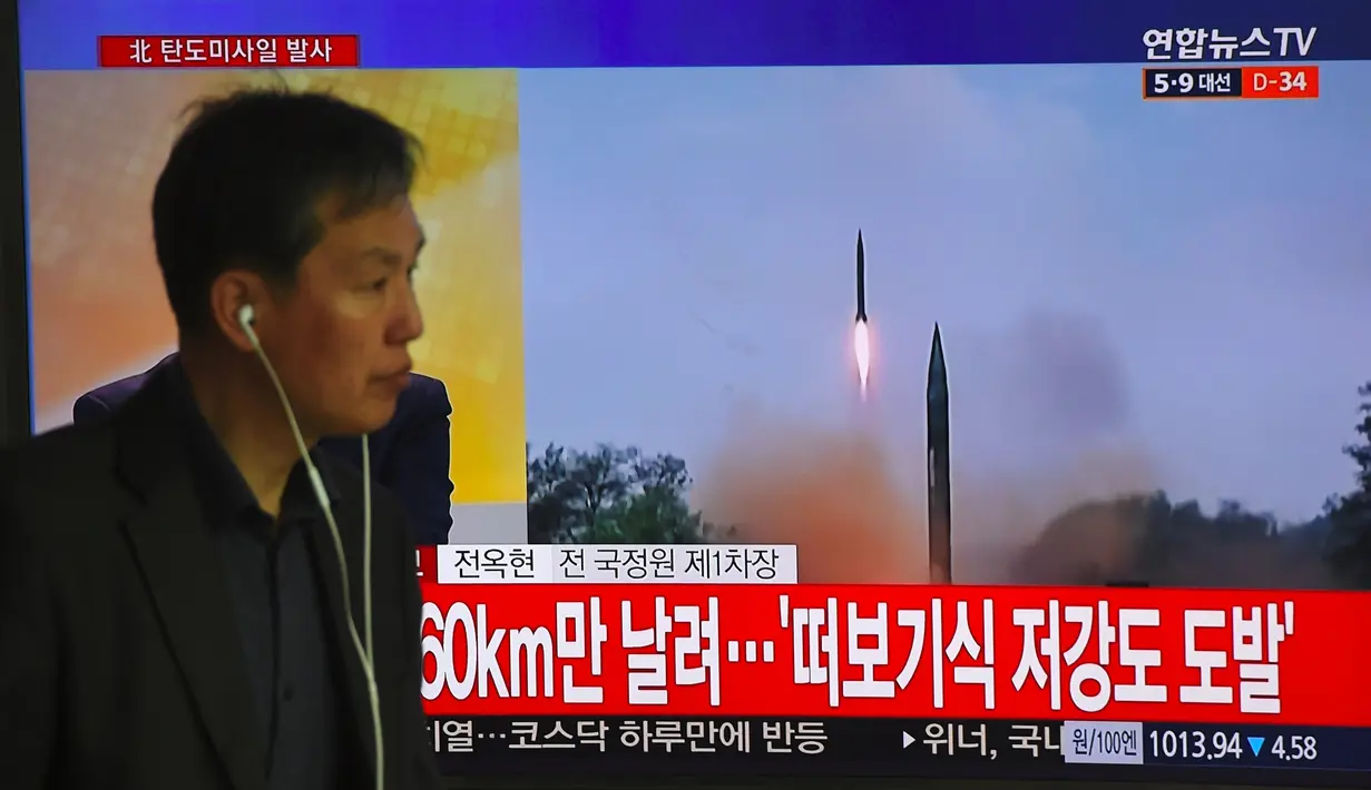 Seorang pria melewati layar televisi yang menyiarkan berita peluncuran rudal oleh Korea Utara (Korut), di sebuah stasiun kereta di Seoul, Korea Selatan, Selasa (5/4). Rudal itu ditembakkan dari wilayah timur Korut ke arah Laut Jepang. (JUNG Yeon-Je/AFP)