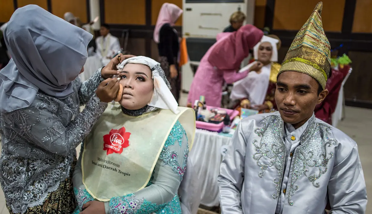 Pasangan pengantin dirias saat akan mengikuti nikah massal di Surabaya, Jawa Timur, Rabu (18/12/2019). Sebanyak 60 pasangan pengantin mengikuti nikah massal yang digelar Dinas Sosial Kota Surabaya. (JUNI KRISWANTO/AFP)