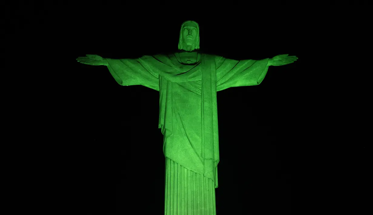 Patung Kristus Penebus raksasa yang terkenal di Rio de Janeiro, Brasil, diterangi dengan lampu hijau pada kesempatan Hari Lingkungan Hidup Sedunia pada Senin (5/6/2023). (CARL DE SOUZA / AFP)
