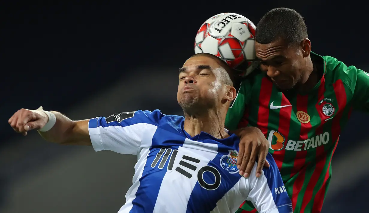 Bek FC Porto, Pepe, berebut bola dengan gelandang Maritimo, Moreno, pada laga lanjutan Liga Portugal di Dragao Stadium, Porto, Kamis (10/6/2020) waktu setempat. Porto menang tipis 1-0 atas Maritimo. (AFP/Jose Coelho/Pool)