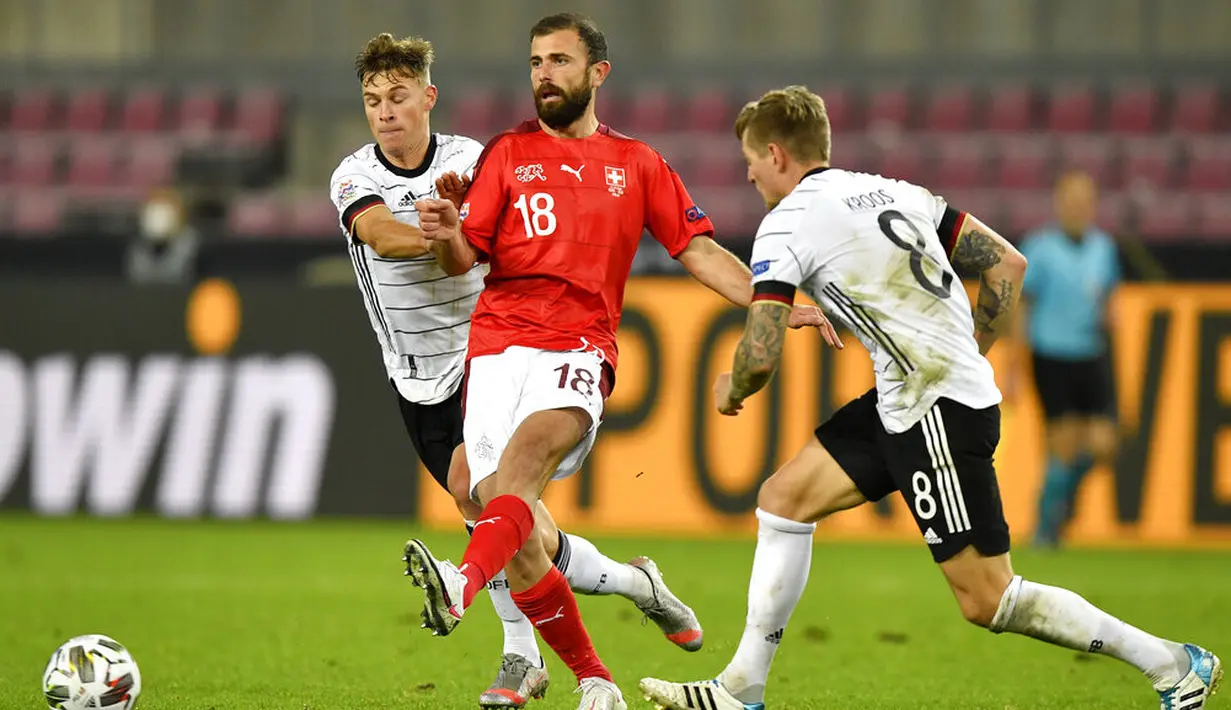 Pemain Swiss Admir Mehmedi (tengah) menendang bola melewati pemain Jerman Toni Kroos (kanan) pada pertandingan UEFA Nations League di Cologne, Jerman, Selasa (13/10/2020). Pertandingan berakhir dengan skor 3-3. (AP Photo/Martin Meissner)