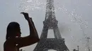 Seorang wanita mendinginkan diri di kolam Trocadero Fountains (air mancur Trocadero) dekat Menara Eiffel di Paris, Kamis (25/7/2019). Gelombang panas di Eropa mencapai puncaknya, bahkan suhu di ibu kota Prancis mencapai di atas 41 derajat Celcius. (Dominique FAGET / AFP)
