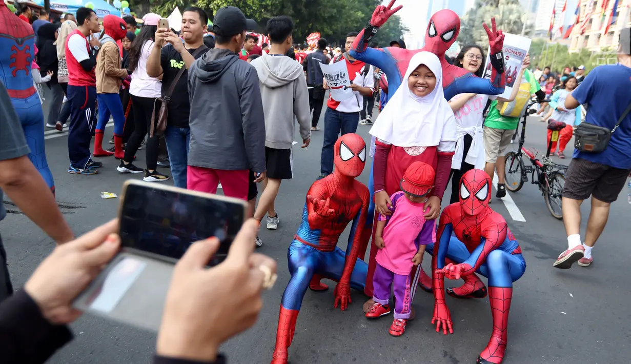 Sejumlah orang dengan kostum Spiderman berfoto bersama anak-anak di  CFD Jalan MH Thamrin, Jakarta, Minggu (6/8). Mereka mengajak warga berswafoto sambil berdonasi untuk panti asuhan. (Liputan6.com/Fery Pradolo)