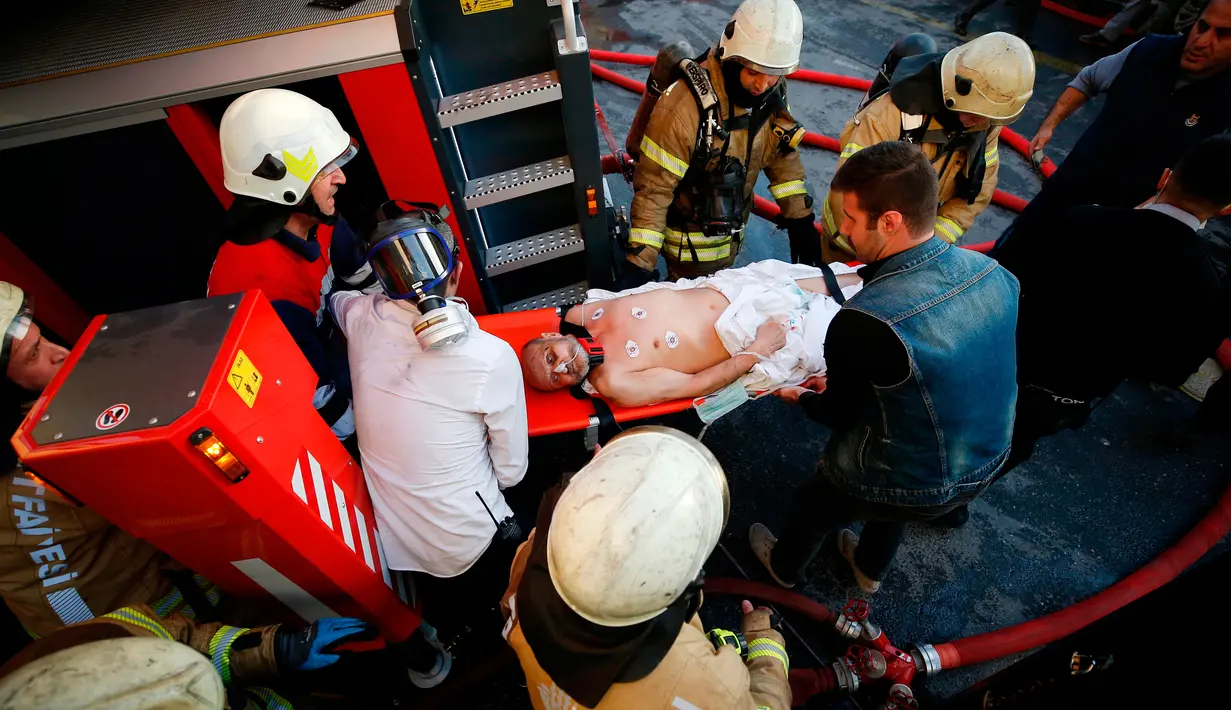 Petugas pemadam kebakaran dan petugas medis mengevakuasi seorang pasien setelah terjadi kebakaran di rumah sakit di distrik Gaziosmanpasa, Istanbul, Turki (5/4). Sebanyak 70 pasien dievakuasi dari peristiwa ini. (AP Photo/ Emrah Gurel)