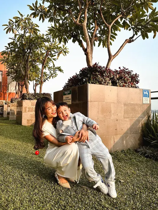 Gaya cantik elegan Fuji mengenakan dress putih yang sederhana, dengan detail kerut di bagian tengah dan slit di bagian tengah bawah. [Foto: Instagram/fuji_an]