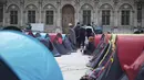 Para imigran berdiri di sebuah kamp darurat yang dibangun di luar balai kota Paris, pada Jumat (25/6/2021). Lebih dari 300 migran mendirikan sekitar 200 tenda di luar balai kota untuk menarik perhatian terhadap kondisi mereka dan menuntut akomodasi. (AP Photo/Lewis Joly)