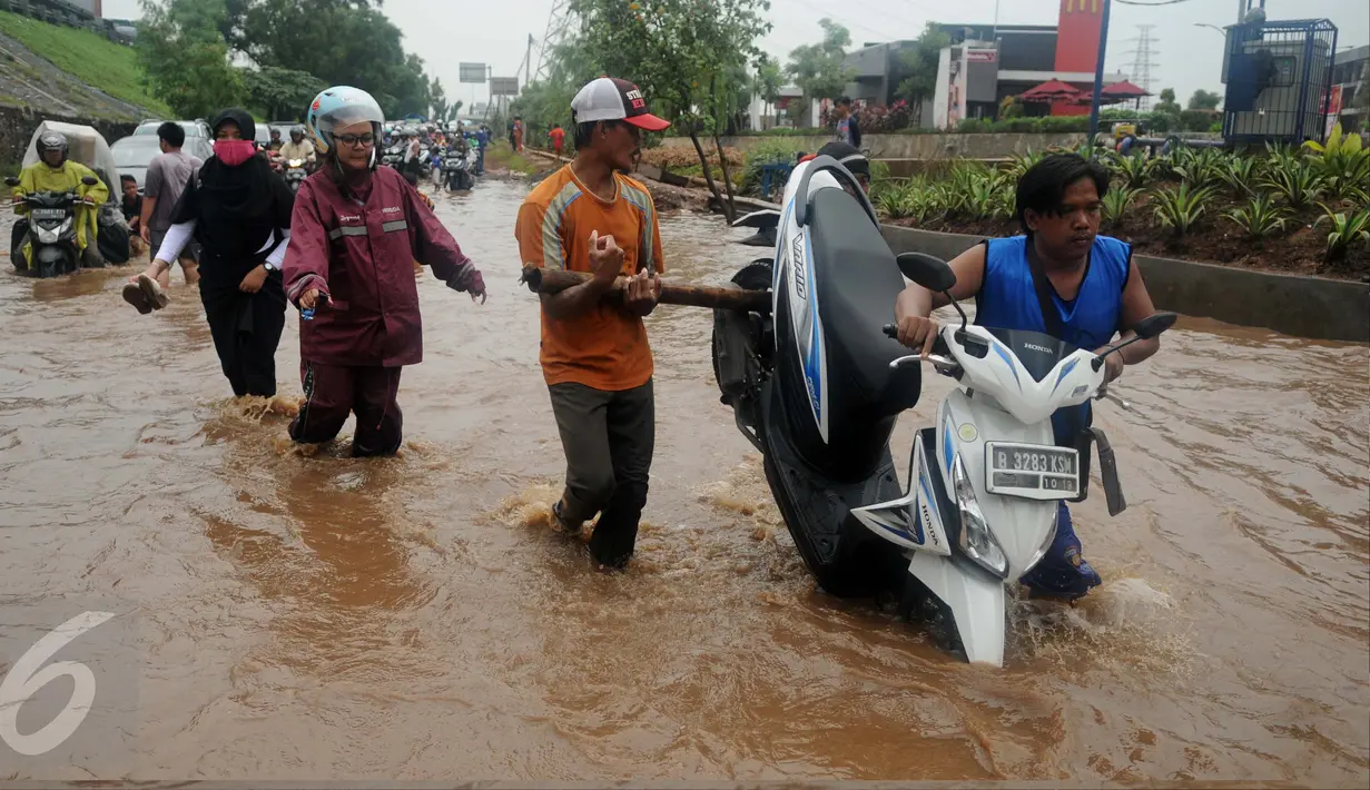 Warga membantu mendorong motor yang mogok saat banjir di Jalan Raya Kalimalang, Caman, Bekasi, Senin (20/2). Akibat banjir dengan ketinggian di atas 60 cm 
