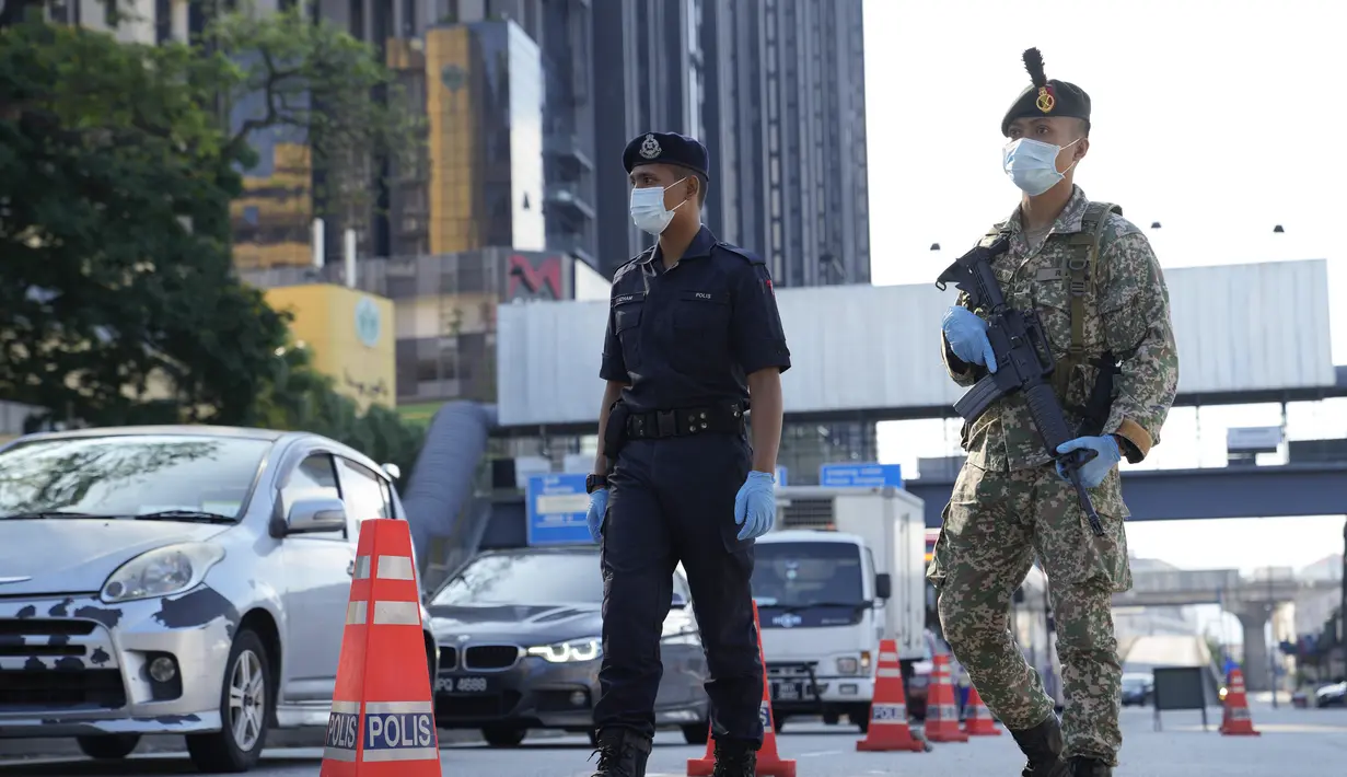 Polisi memeriksa penumpang di kendaraan di penghalang jalan pada hari pertama Perintah Kontrol Gerakan Penuh (MCO) di Kuala Lumpur, Malaysia, Selasa (1/6/2021). Mal dan sebagian besar bisnis di Malaysia tutup pada Selasa karena negara itu memulai penguncian total kedua . (AP Photo/Vincent Thian)