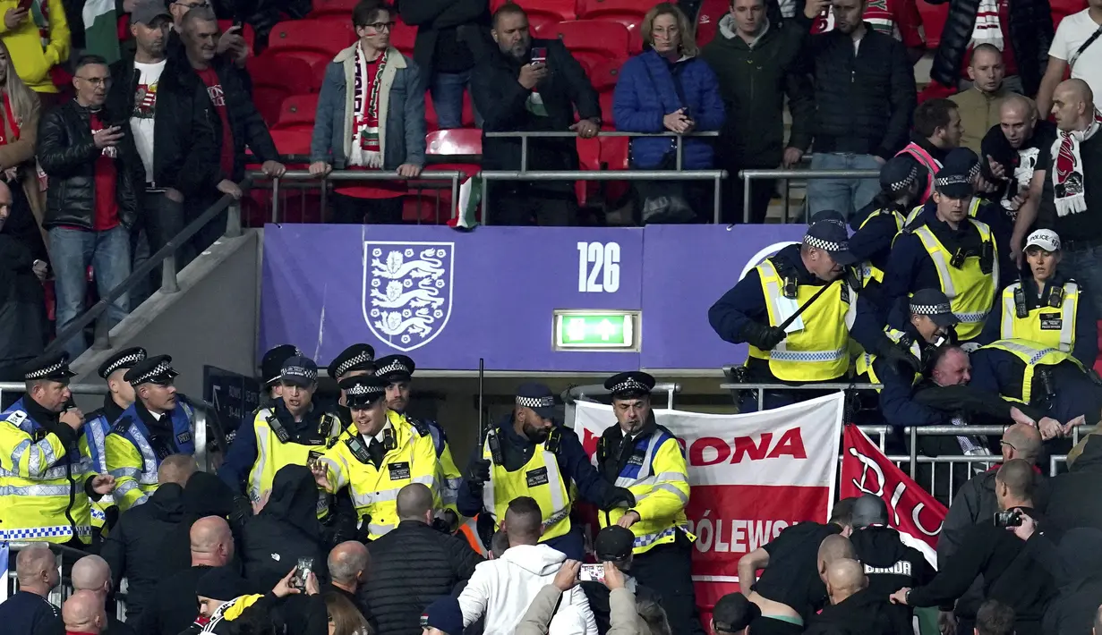Bentrokan suporter Hungaria dengan polisi saat dimulainya laga Kualifikasi Piala Dunia 2022 melawan Inggris di Stadion Wembley, Rabu (13/10/2021) dini hari WIB. Bentrokan terjadi saat polisi berusaha menangkap penonton yang melakukan pelecehan rasial terhadap petugas stadion. (Nick Potts/PA via AP)