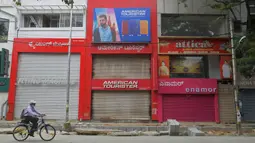 Seorang pria bersepeda di depan toko-toko yang tutup di area komersial saat pemberlakukan lockdown di Bangalore, Rabu (15/7/2020). Pusat IT India, Bangalore, kembali memberlakukan lockdown selama seminggu dimulai dari 14 Juli 2020 setelah adanya lonjakan kasus Covid-19. (Manjunath Kiran/AFP)