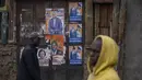 Warga berjalan melewati poster kampanye pemilihan yang menunjukkan kandidat presiden Raila Odinga dan pasangannya Martha Karua, di sebuah jalan di daerah Kibera, Nairobi, Kenya, Kamis, 11 Agustus 2022. Rakyat Kenya menunggu hasil pemilihan presiden yang berlangsung ketat namun tenang di mana jumlah pemilih lebih rendah daripada biasanya. (AP Photo/Ben Curtis)