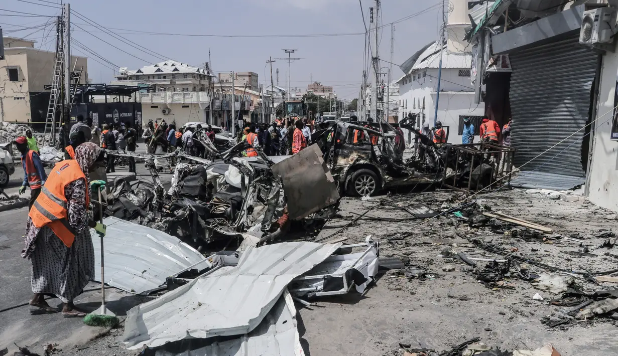 Tim penyelamat dan pengamat berkumpul di dekat puing-puing di lokasi serangan bom mobil bunuh diri di dekat pos pemeriksaan keamanan di Mogadishu, Somalia (13/2/2021). Ledakan ini adalah ledakan besar kedua di ibu kota Somalia dalam beberapa pekan terakhir. (Abdirazak Hussein FARAH / AFP)