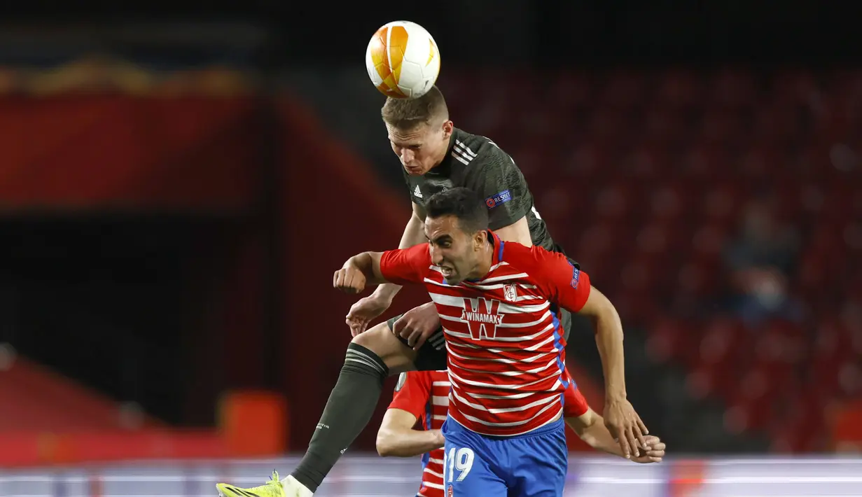Gelandang Manchester United, Scott McTominay berebut bola dengan pemain Granada, Angel Montoro pada pertandingan leg pertama perempat final Liga Europa di stadion Los Carmenes di Granada, Spanyol, Jumat (9/4/2021). MU menang atas Granada 2-0. (AP Photo/Fermin Rodriguez)