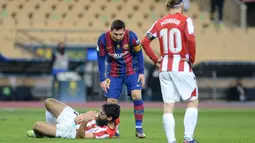 Penyerang Barcelona, Lionel Messi memeriksa penyerang Athletic Bilbao, Asier Villalibre setelah memukulnya pada pertandingan final Piala Super Spanyol di stadion La Cartuja, Senin (18/1/2021). Messi kini akan disanksi larangan tampil sebanyak empat sampai 12 laga. (AFP/Cristina Quicler)
