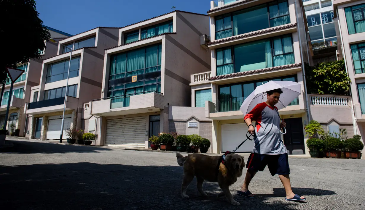 Pejalan kaki melintasi villa yang diyakini sebagai salah satu kediaman Kim Jong-nam di Macau, Kamis (16/2). Macau pernah menjadi rumah sekaligus tempat kakak tiri Kim Jong-un itu mencari uang selama pelarian dari rezim Korea Utara. (Anthony WALLACE/AFP)