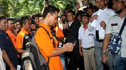 Prio Santoso (24) tersangka pembunuh Deudeuh Alfi Sahrin memegang telepon seluler saat rekonstruksi kejahatan di Tebet, Jakarta (6/5/2015). Tersangka melakukan 21 adegan, dari mulai pertama tiba di lokasi hingga pembunuhan. (Liputan6.com/Yoppy Renato)