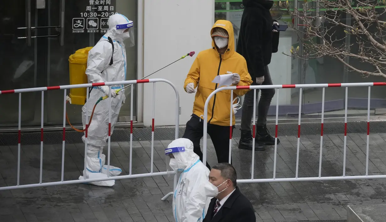 Pekerja mendisinfeksi seorang pria di luar gedung perkantoran yang ditutup setelah kasus covid-19 terdeteksi, Minggu (13/3/2022). Pihak berwenang memperketat kontrol akses ke Shanghai setelah jumlah kasus baru covid-19 di timur laut China meningkat tiga kali lipat. (AP Photo/Ng Han Guan)
