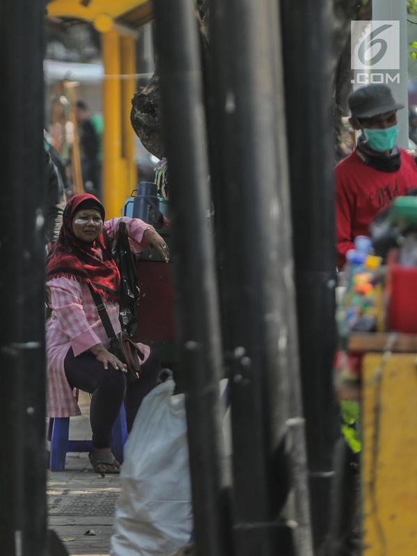 Pedagang menggunakan odol diwajah menghindari sisa gas air mata pasca bentrok massa dengan aparat di Palmerah, Jakarta, Kamis (26/9/2019). Banyak masyarakat yang melintas dan warga sekitar perih pada mata hingga bersin akibat sisa gas air mata pasca bentrokan kemarin. (Liputan6.com/Faizal Fanani)