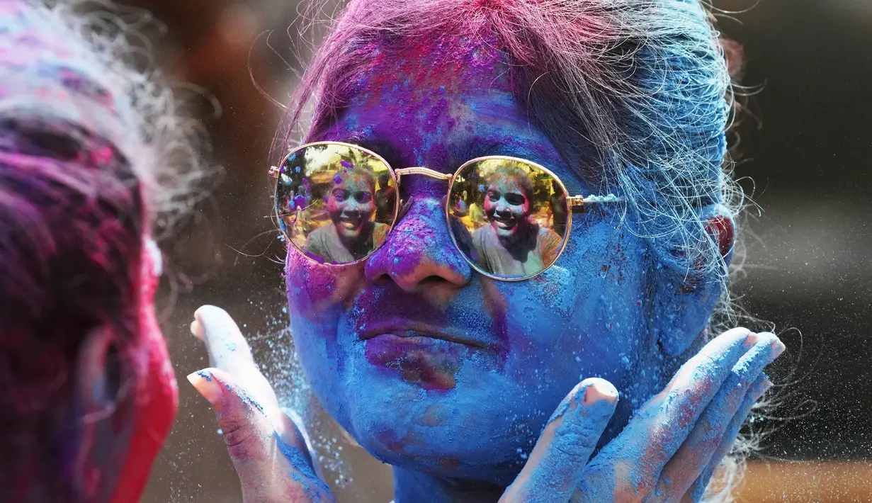 Orang yang bersuka ria diolesi bedak berwarna di wajah orang lain selama perayaan menandai Holi, festival warna Hindu, di Mumbai, India (18/3/2022).  Holi, festival warna Hindu, juga menandai datangnya musim semi. (AP Photo/Rajanish Kakade)