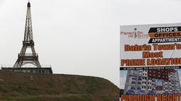 Sebuah spanduk terlihat dipasang dengan latar belakang replika Menara Eiffel yang berdiri di bukit Kota Bahria, pinggiran Islamabad, Pakistan, 16 Maret 2016. Replika tersebut memiliki tinggi mencapai 80 meter. (REUTERS/Caren Firouz)