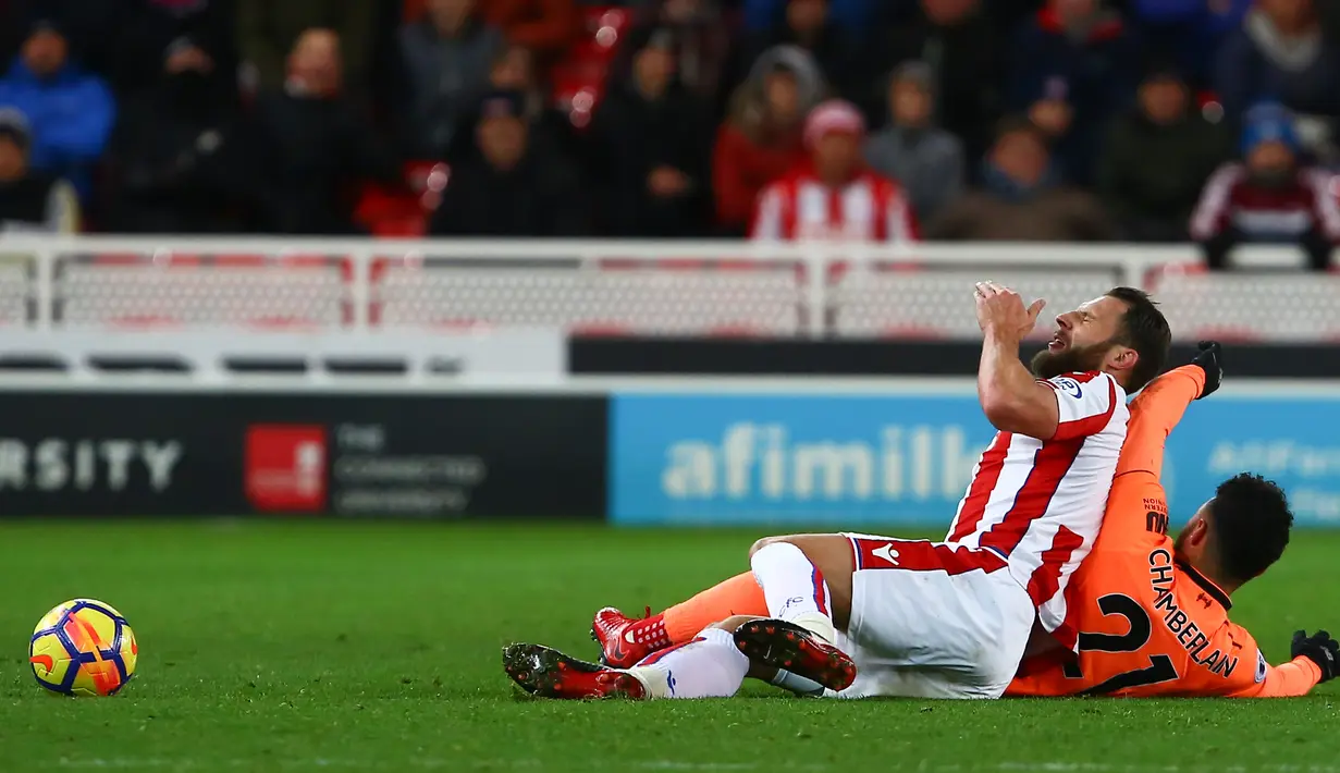Bek Stoke City, Erik Pieters berebut bola dengan gelandang Liverpool, Alex Oxlade-Chamberlain pada pekan ke-14 Premier League di Bet365 Stadium, Kamis (30/11). Liverpool berhasil membantai Stoke City dengan skor 3-0. (Geoff CADDICK/AFP)