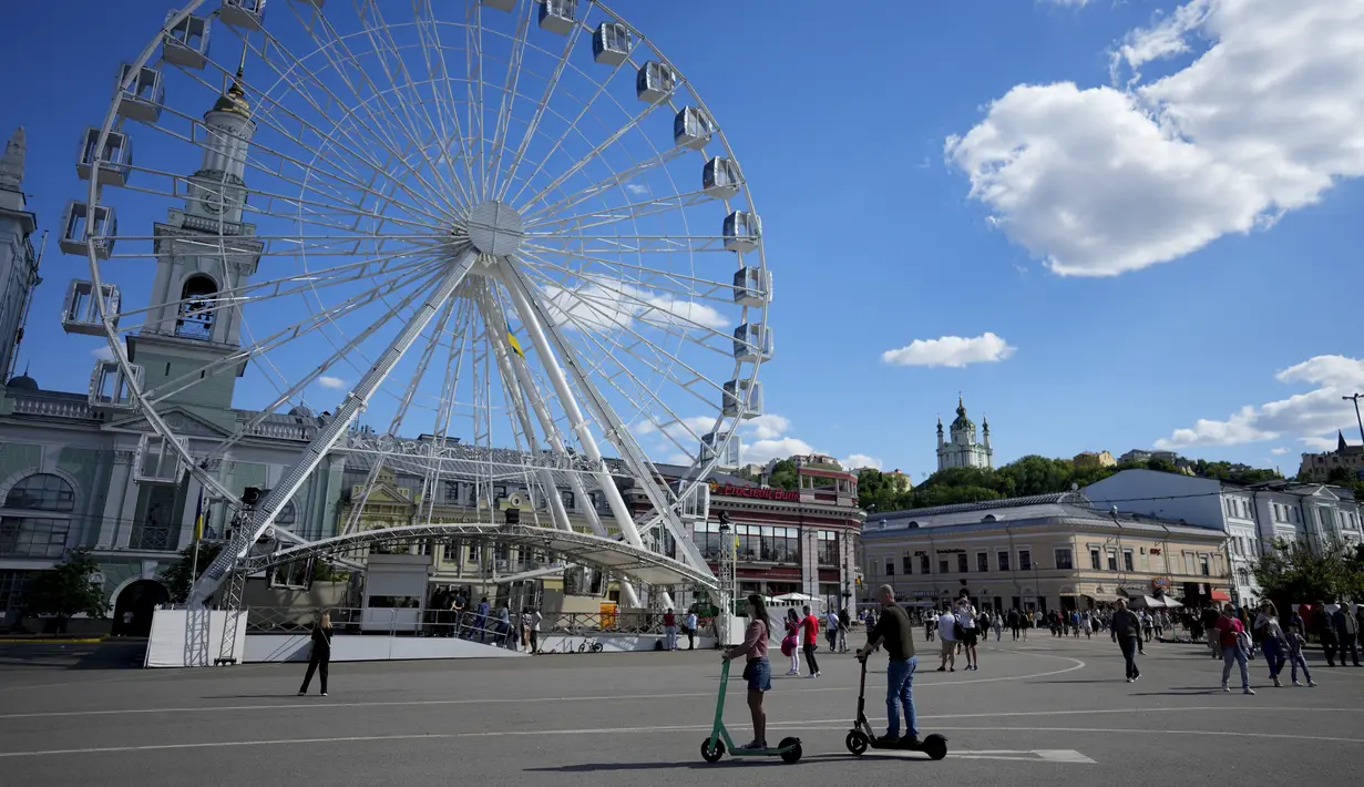 <p>Pasangan mengendarai skuter selama perayaan Hari Kiev di Kiev, Ukraina, Minggu (29/5/2022). Ibu kota Ukraina merayakan ulang tahun pendiriannya setiap Minggu terakhir bulan Mei. Kiev merayakan peringatan 1540 tahun pendiriannya, di mana tahun ini dirayakan di bawah darurat militer. (AP Photo/Natacha Pisarenko)</p>