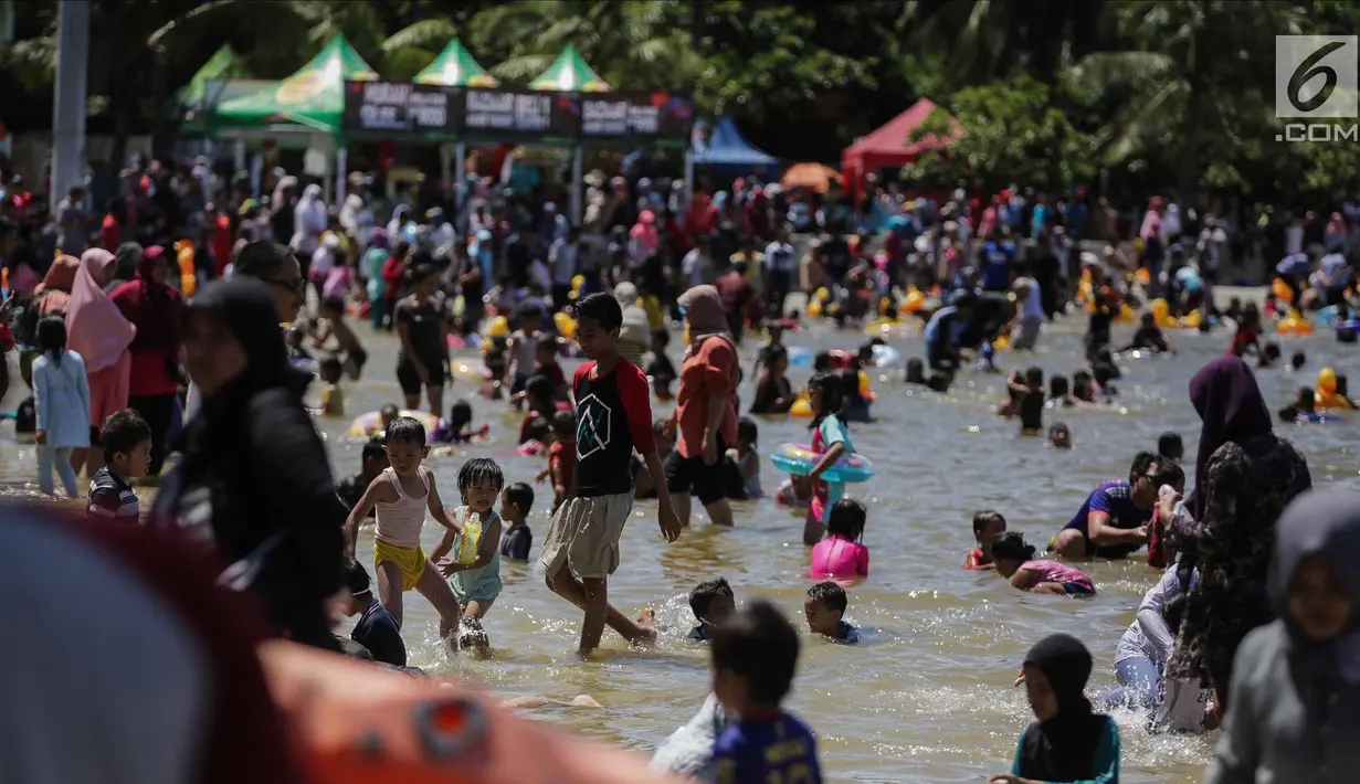 Sejumlah anak bermain air di pantai Ancol, Jakarta, Senin (25/12). Pengunjung lebih memilih liburan ke Pantai Ancol karena gratis, tidak dikenai biaya tambahan. (Liputan6.com/Faizal Fanani)