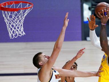 Pebasket Los Angeles Lakers, LeBron James, berusaha memasukkan bola saat melawan Denver Nuggets pada laga NBA di The Arena, Senin (11/8/2020). LA Lakers menang dengan skor 124-121. (AP Photo/Ashley Landis, Pool)