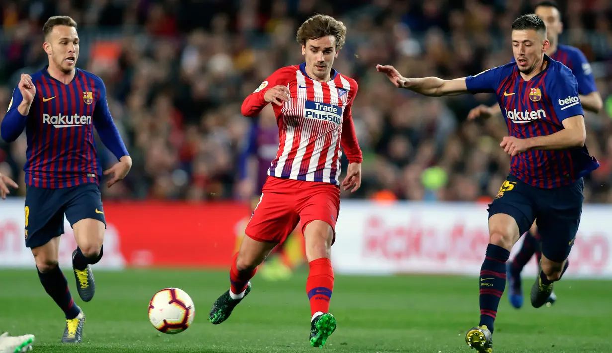 Striker Atletico Madrid, Antoine Griezmann mengiring bola dari kawalan dua pemain Barcelona selama pertandingan Liga Spanyol di Camp Nou (6/4/2019). Barcelona dilaporkan akan mengontrak  Griezmann selama lima tahun. (AP Photo/Manu Fernandez)