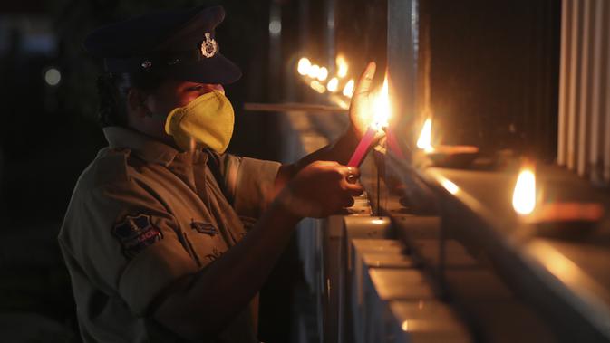 Seorang polisi wanita menyalakan lampu tembikar untuk menandai perjuangan melawan pandemi virus corona COVID-19 di Hyderabad, India, Minggu (5/4/2020). India memberlakukan lockdown selama 21 hari di seluruh negeri untuk memerangi wabah virus corona. (AP Photo/Mahesh Kumar A.)