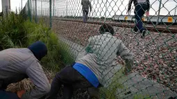 Imigran gelap ketika berusaha melewati pagar keamanan terminal Eurotunnel di Coquelles dekat Calais di Prancis, 29 Juli 2015. Ribuan imigran tersebut mencoba memasuki Terowongan Channel menuju Inggris melalui Prancis. (REUTERS/Pascal Rossignol)