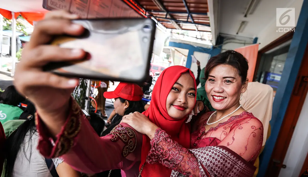Pengemudi ojek online wanita berswafoto jelang peragaan busana di Rawamangun, Jakarta, Jumat (20/4). Kegiatan digelar menyambut Hari Kartini yang jatuh pada 21 April mendatang. (Liputan6.com/Fery Pradolo)