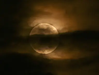 Bulan terlihat melalui awan saat gerhana bulan sebagian di Srinagar, India, Jumat (5/5/2023). Gerhana Bulan Penumbra akan muncul pada Jumat (5/5/) hingga Sabtu (6/5) dinihari. (TAUSEEF MUSTAFA / AFP)