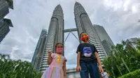 Anak-anak yang mengenakan masker berpose untuk difoto di depan Menara Kembar Petronas di Kuala Lumpur, Malaysia, pada 3 Oktober 2020. Malaysia melaporkan tambahan 317 kasus terkonfirmasi COVID-19 pada Sabtu (3/10), sehingga totalnya bertambah menjadi 12.088. (Xinhua/Chong Voon Chung)