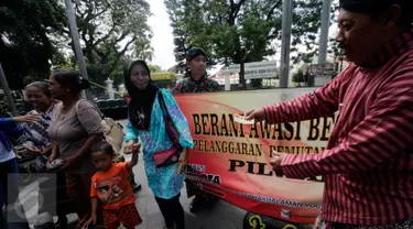 Petugas Panwas Kota Yogyakarta membagikan stiker saat sosialisasi pilkada bebas uang politik di kawasan Titik Nol Kilometer, Senin (1/8). Kegiatan tersebut untuk mensosialisasikan pelaksanaan pilkada serentak 2017 mendatang. (Liputan6.com/Boy Harjanto)