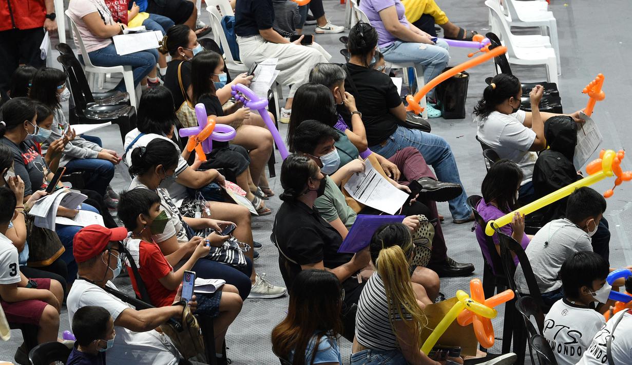 Anak-anak bersama walinya menunggu giliran disuntik vaksin Covid-19 Pfizer-BioNtech untuk anak-anak berusia 5-11 di sebuah gym di San Juan City, pinggiran kota Manila, Filipina pada 7 Februari 2022. (Ted ALJIBE / AFP)