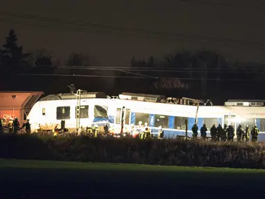 Sejumlah petugas berdiri di samping gerbong yang rusak usai terjadinya tabrakan kereta di Meerbusch, Jerman, (5/12). Akibat musibah tersebut puluhan orang terluka saat kereta penumpang bertabrakan dengan kereta kargo. (Arnulf Stoffel/dpa via AP)