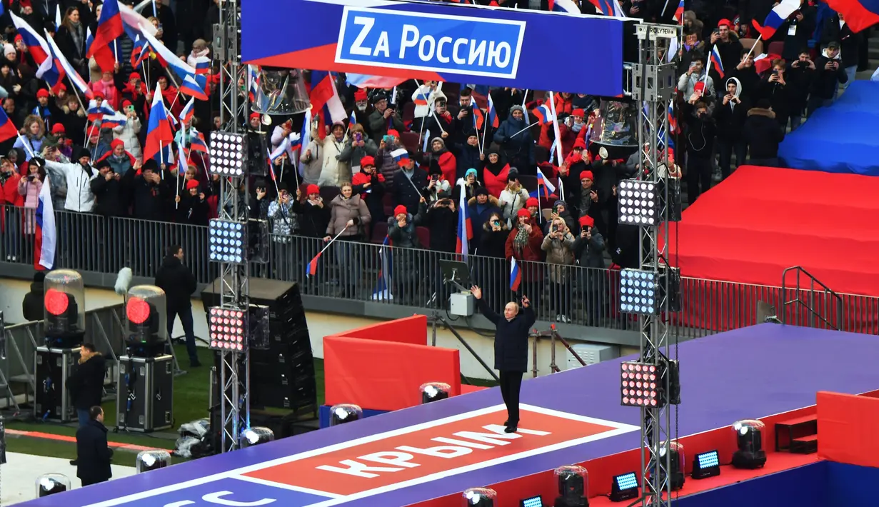 Presiden Rusia Vladimir Putin melambai kepada orang-orang yang berkumpul untuk menghadiri konser perayaan  delapan tahun referendum tentang status negara bagian Krimea dan Sevastopol serta penyatuannya kembali dengan Rusia, di Moskow, Rusia (18/3/2022). (Evgeny Biyatov/Sputnik Pool Photo via AP)