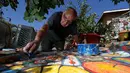 Gonzalo Duran menyusun pecahan keramik menjadi mozaik di salah satu sudut Mosaic Tile House Venice, California, AS, (26/9). Rumah ini dipenuhi mozaik dari kepingan keramik, genteng, souvenir, mainan hingga barang-barang bekas. (REUTERS/Mario Anzuoni)