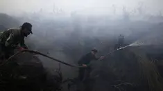 Anggota TNI memadamkan api di perkebunan kelapa sawit di Desa Padamaran, Ogan Komering Ilir , Sumatera Selatan, Sabtu (12/9/2015). Kebakaran lahan menyebabkan kabut asap di sejumlah wilayah dan mengganggu jadwal penerbangan. (REUTERS/Beawiharta)