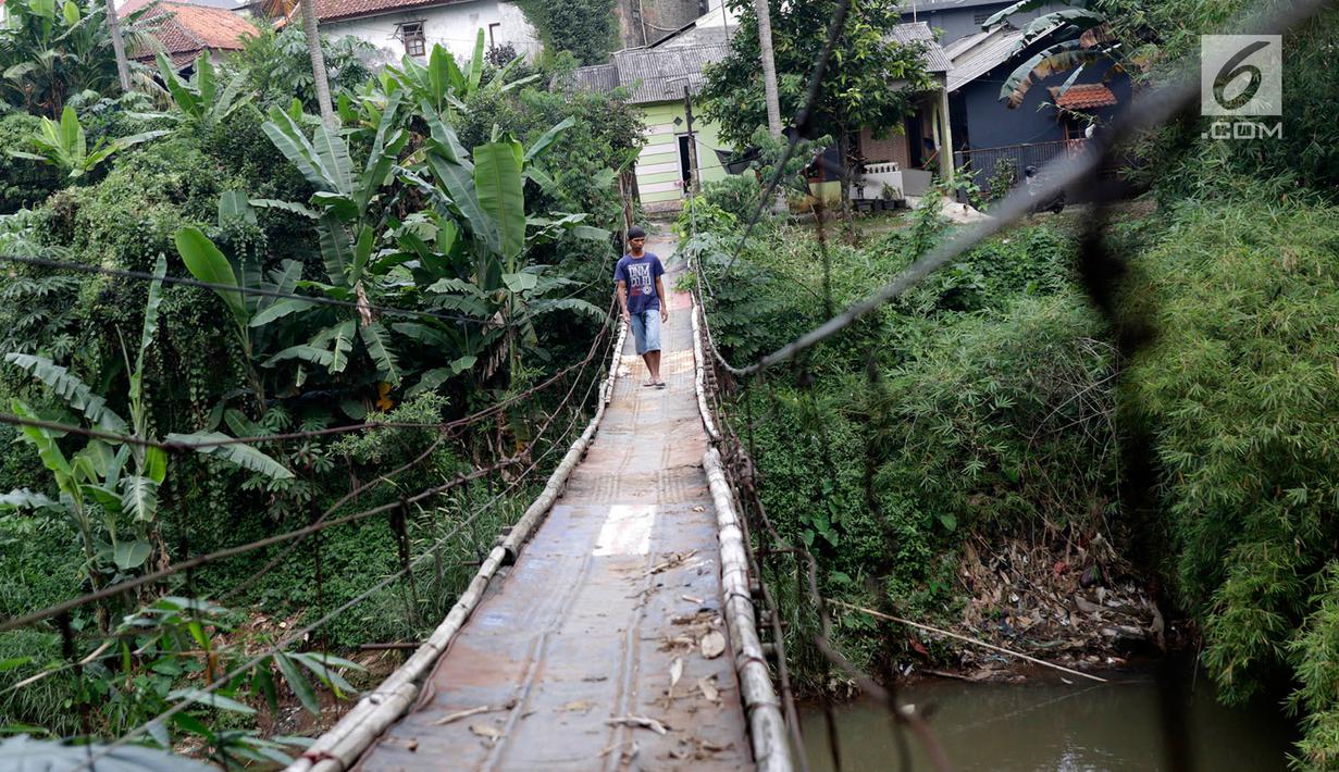 Warga melintasi jembatan penyeberangan buatan warga di kawasan Lenteng Agung, Jakarta, Rabu (24/5). Meskipun kondisinya memprihatinkan, warga setempat tetap menggunakan jembatan tersebut. (Liputan6.com/Immanuel Antonius)